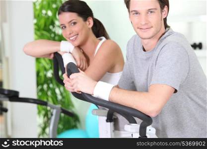 two young people resting on cardio machines