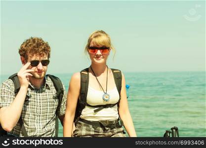 Two young people tourists hiking by sea ocean water. Backpackers couple on summer vacation trip journey.. Two people tourists hiking by sea ocean.