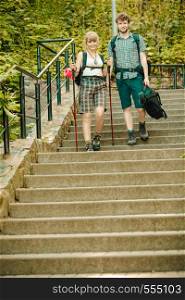 Two young people tourists hiking walking on stairs. Man and woman with trekking poles sticks.. Two people tourists hiking walking on stairs.