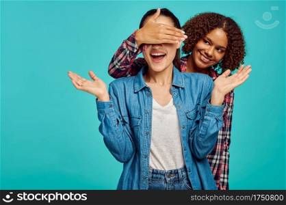 Two young playful ladies, blue background, positive emotion. Face expression, female person looking on camera in studio, emotional concept, feelings. Two young playful ladies, positive emotion