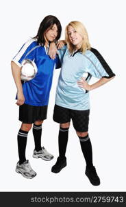 Two young pretty soccer woman, holding a soccer ball and wearing theuniform of there club, standing in the studio for light gray background.