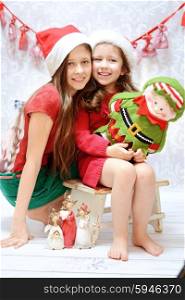 Two young sisters wearing santa hats