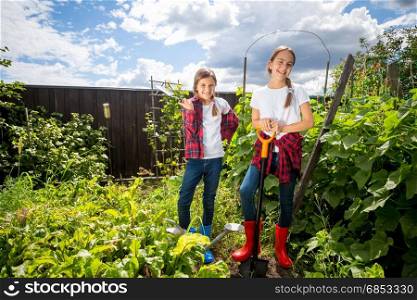 Two young sisters working at backyard garden at sunny day