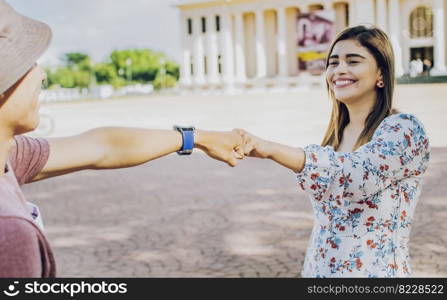 Two young smiling teenagers bumping fists in the street. Close up of guy and girl shaking fists in the street. A guy and girl shaking hands on the street