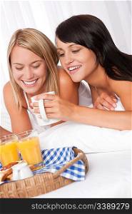Two young smiling women, lesbian couple, having breakfast in bed