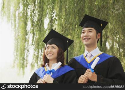 Two Young University Graduates Holding Diplomas