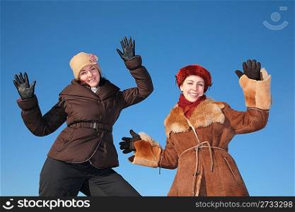 two young woman posing agains blue sky in winter
