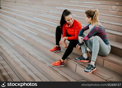 Two young woman resting on stairs after running