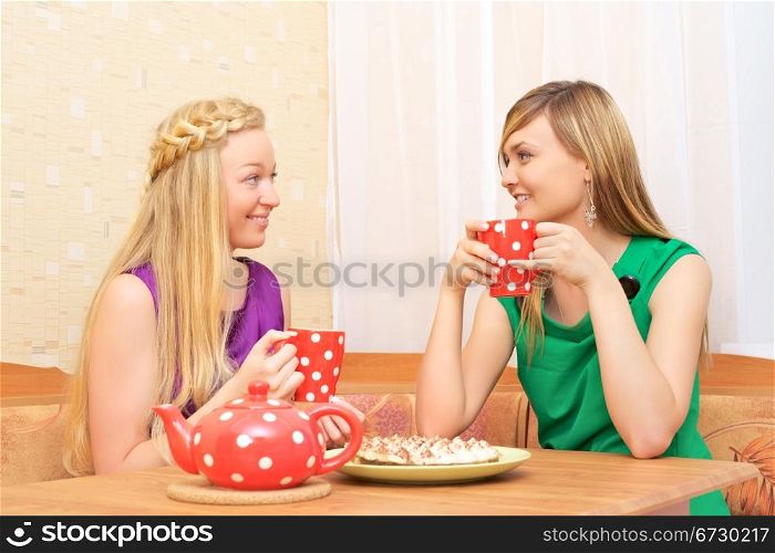 two young woman sitting at a table having tea