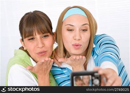 Two young woman taking their picture and blowing kisses