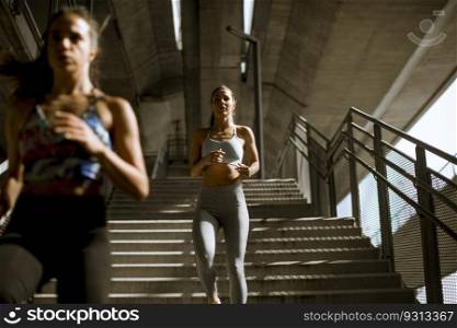 Two young woman workout down stairs in urban environment