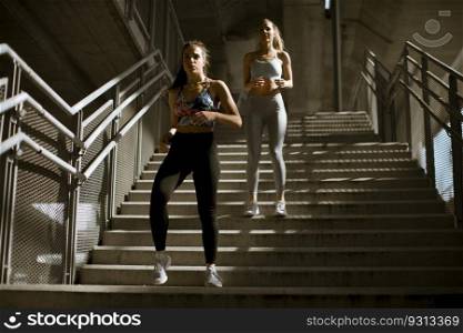 Two young woman workout down stairs in urban environment