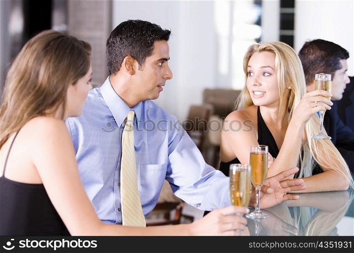 Two young women and a mid adult man sitting at a bar counter