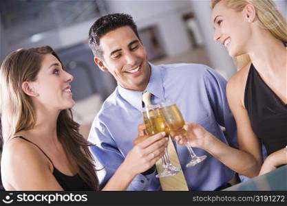 Two young women and a mid adult man toasting