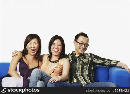 Two young women and a young man sitting on a couch