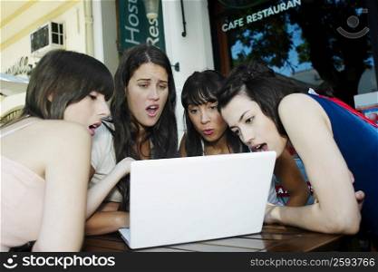 Two young women and two mid adult women looking at a laptop