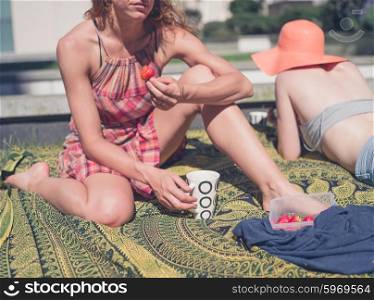 Two young women are relaxing on the grass outside in an urban area on a sunny day