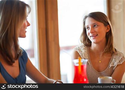 Two young women chatting in cafe bar
