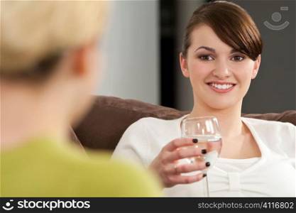 Two young women chatting while drinking glasses of mineral water