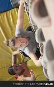 Two young women climbing in an indoor climbing gym, directly above