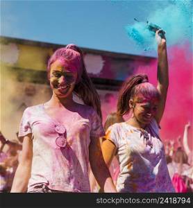 two young women covered with holi color dancing holi festival