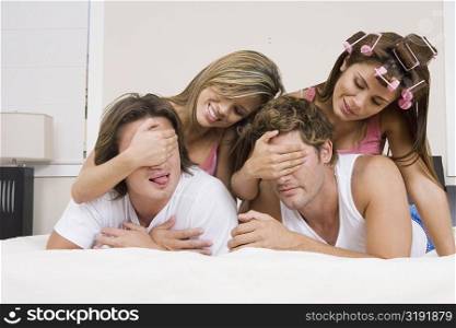 Two young women covering eyes of their boyfriends