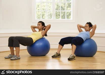 Two young women doing ab workout on balance balls.
