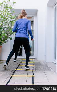 Two young women doing agility ladder exercise on a terrace