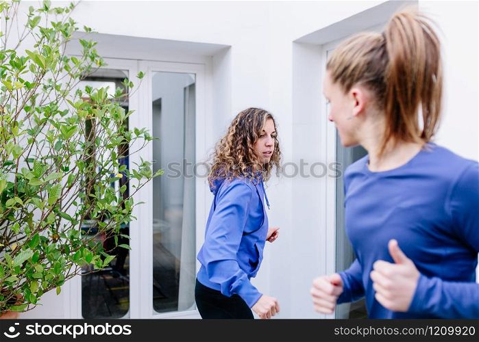 Two young women doing exercise together on a terrace