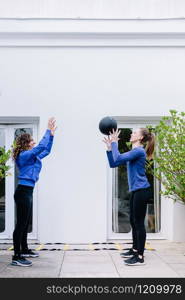 Two young women doing exercise together with medicine ball on a terrace