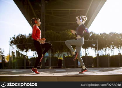 Two young women doing gymnastic exercises outdoor in urban enviroment