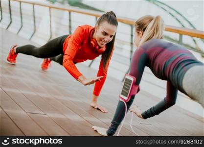 Two young women doing plank on riverside after running