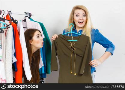 Two young women during shopping time picking perfect casual short dress for friend.. Women clothes shopping choosing dress