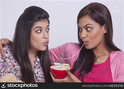 Two young women eating noodles