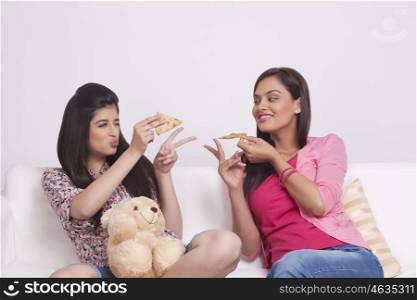Two young women eating pizza