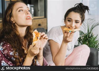 two young women eating pizza home