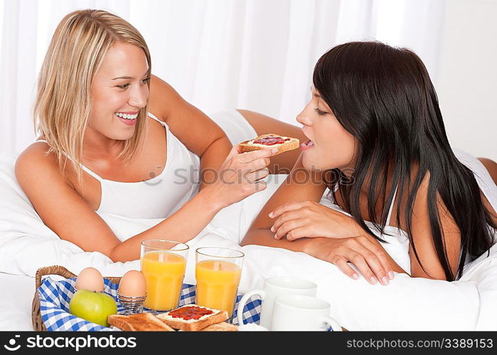 Two young women eating toast with marmalade, lesbian couple