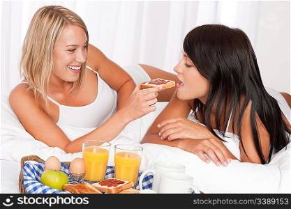 Two young women eating toast with marmalade, lesbian couple
