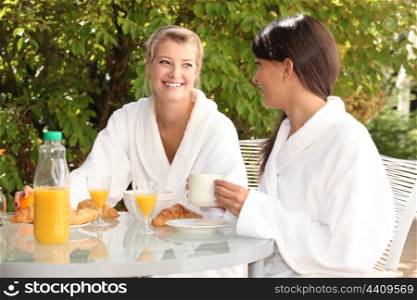 Two young women having breakfast in the garden