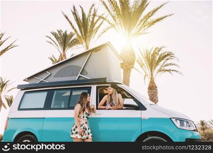 Two young women having fun in her van near the beach