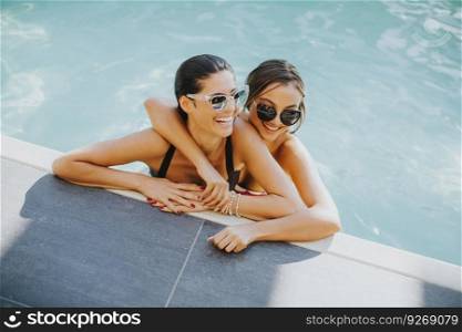 Two young women having fun in the pool at sunny summer day