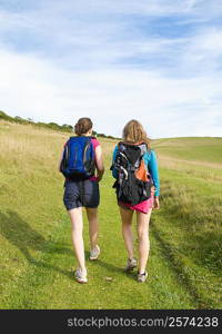 Two young women hikers climb up hill