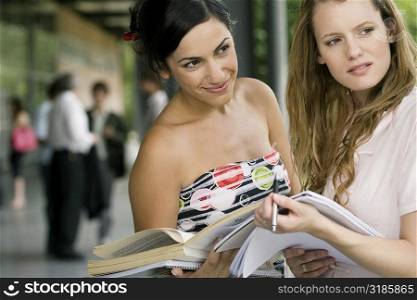 Two young women holding books