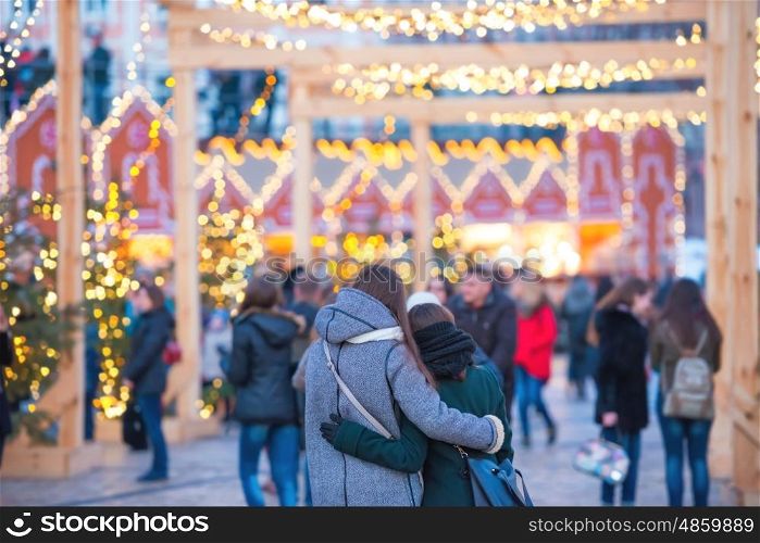 Two young women hugging on the street at holiday night