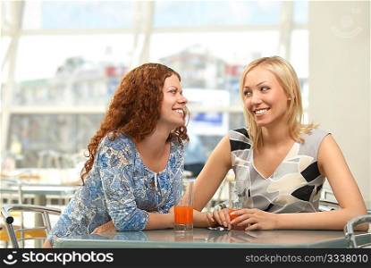 Two young women in a cafe look in one side