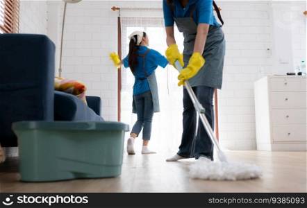 Two young women in uniform are cleaning the living room at home.