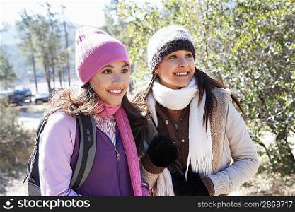 Two young women in warm clothes standing outdoors smiling.