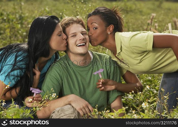 Two young women kissing a young man