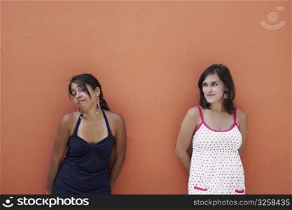 Two young women leaning against a wall