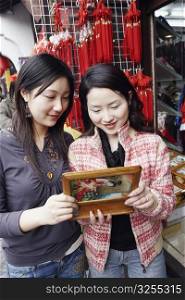 Two young women looking at a jewelry box smiling